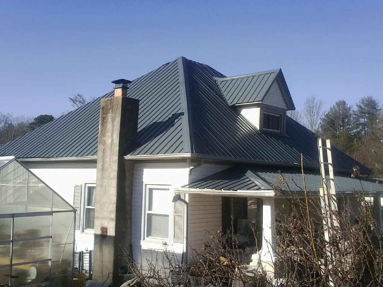 Dark blue standing seam metal roof on a white farmhouse with dormer — Slate & Tile Roof Repair by Roofing Brothers in Boardman