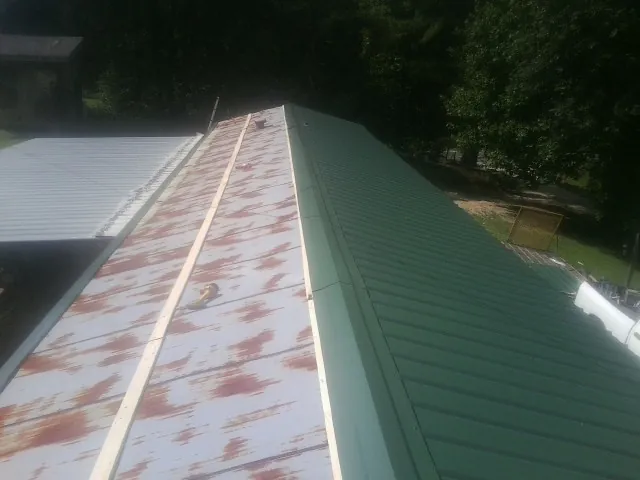 Old rusted panels beside newly installed green metal roofing — Wind Damage Roof Repair by Roofing Brothers in Boardman