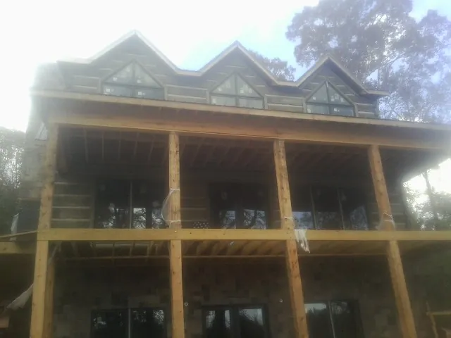 Dormers and porch framing on a large log home under construction — Roof Coating work by our crew in Boardman