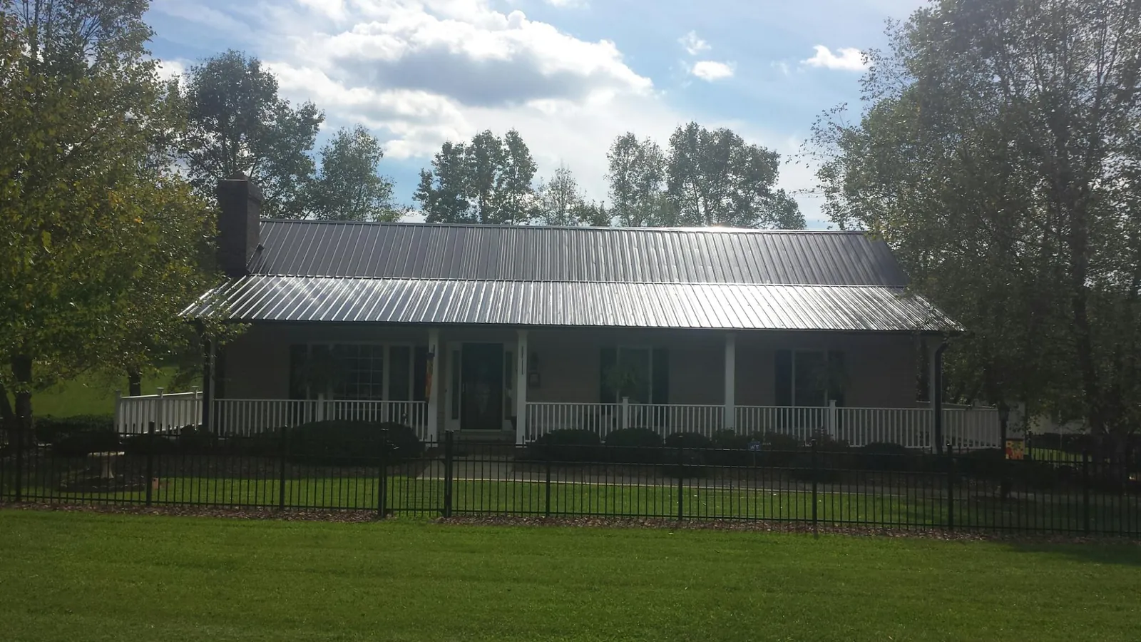 Gray metal roof on a brick ranch with a full width front porch — Gutter Guard Installation work by our crew in Boardman